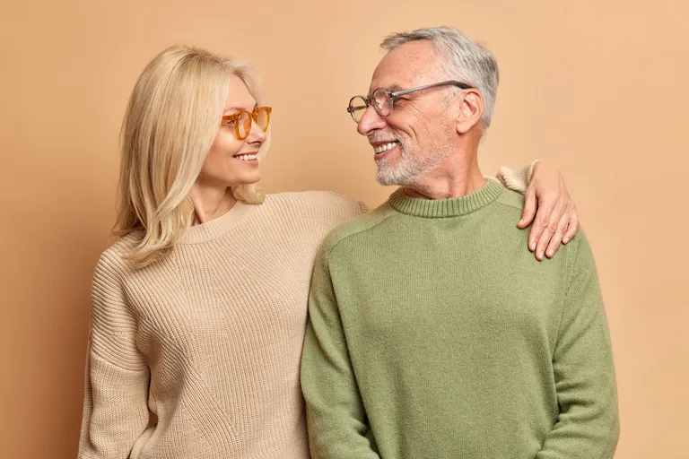 A smiling couple in cozy sweaters stands closely together in Florida